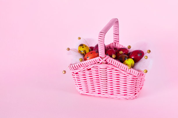 彩色鹌鹑蛋在一个小的粉红色柳条篮子在粉红色的背景图片下载