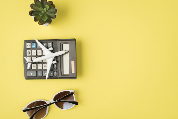 俯视图照片的飞机太阳镜和飞机模型计算器上孤立的淡黄色背景与copyspace图片下载