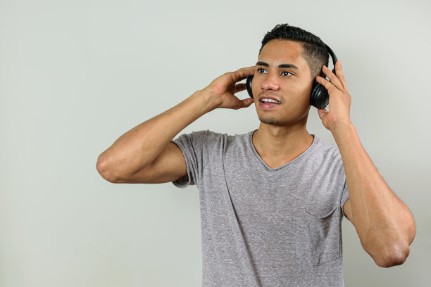 28岁的巴西人，双手拿着无线耳机，听着音乐，看着地平线。图片下载