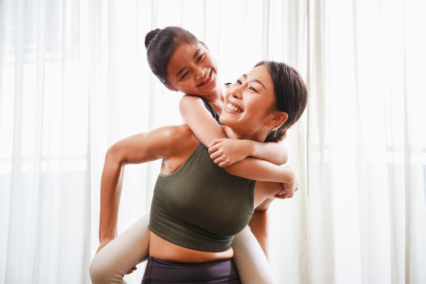 亚洲年轻母亲教她的女儿瑜伽姿势和一起锻炼瑜伽垫在客厅图片下载