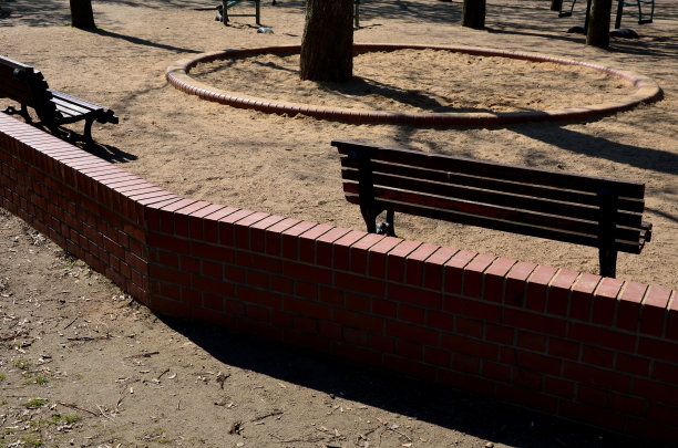 桑迪的孩子和操场在公园的树林中。低矮的砖墙与周围环境相分离。圆圈为小游客定义了一个沙坑图片下载