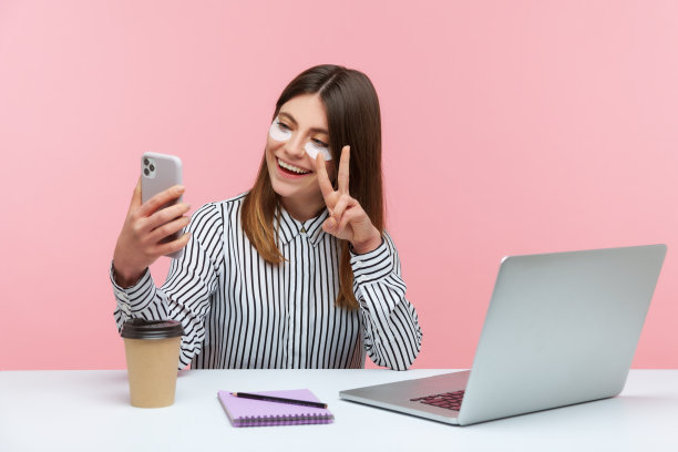 积极的女性，眼罩下显示和平姿态，自拍或通过智能手机视频通话坐在家里的办公室图片下载