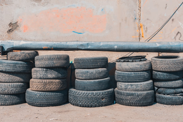 废旧汽车轮胎堆在垃圾场的一堵墙上图片下载