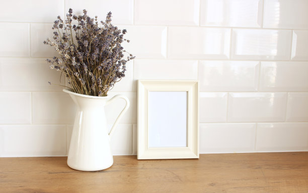 厨房内部的特写。白砖墙，地铁瓷砖，木桌。肖像空木框模型与现代花瓶与薰衣草。现代北欧设计。图片下载