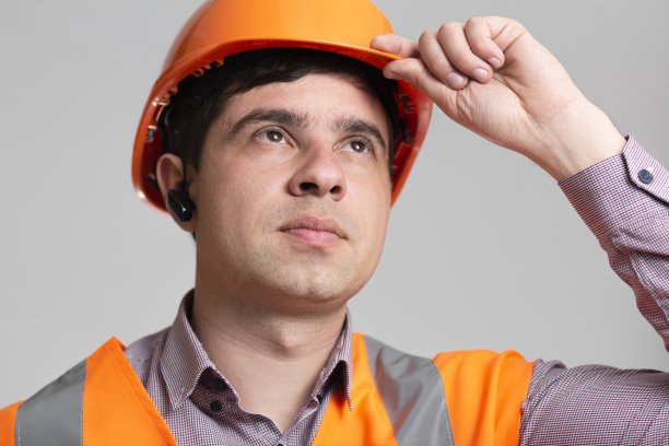 肖像的年轻建筑工人在灰色的工作室背景，面对成功的工程师图片下载