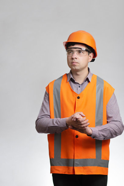 年轻的建筑工人戴着安全帽，在灰色的工作室背景上摩擦设计方案图片下载