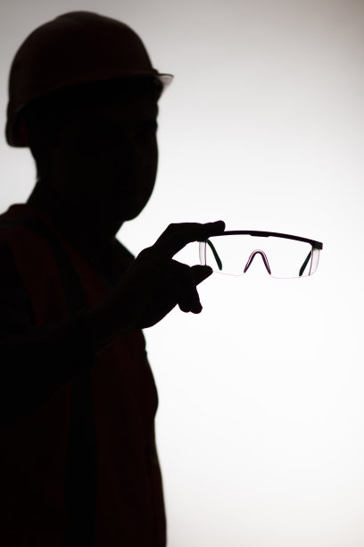 暗黑剪影的建设者与保护眼镜在手伸出在照相机上白色孤立的背景，个人保护设备的概念图片下载