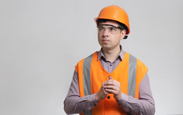 年轻的建筑工人戴着安全帽，在灰色的工作室背景上摩擦设计方案图片下载