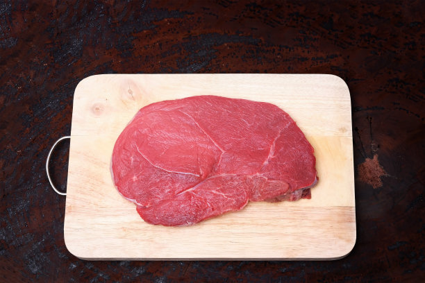 生鲜牛肘牛排切在木板上，放在硬木桌上图片下载