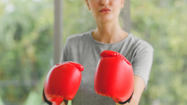 肖像年轻的健身运动妇女穿着运动服与红色拳击手套打。选择手套上的焦点。健康的生活方式的概念图片下载