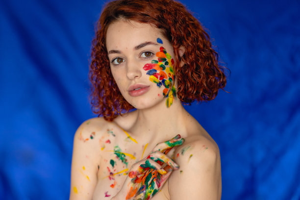 红色卷发女人的特写肖像，年轻愉快，被颜料染污。图片下载