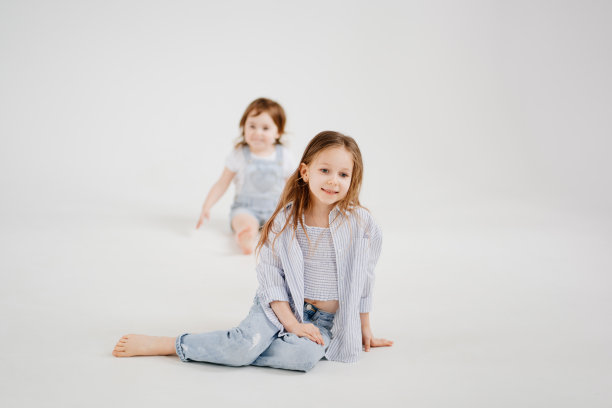 穿着牛仔裤和衬衫的小女孩在白色背景下摆姿势。图片下载