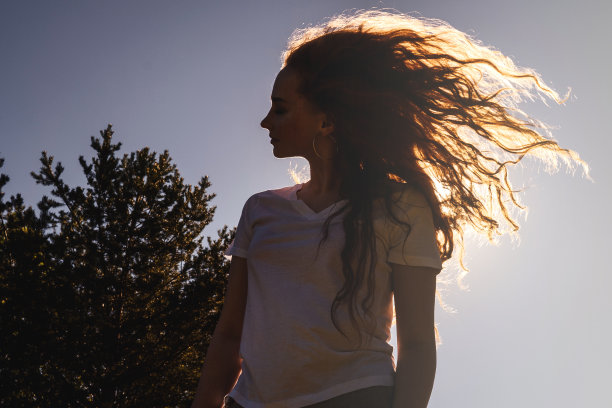 阳光下留着长发的快乐女人。图片下载