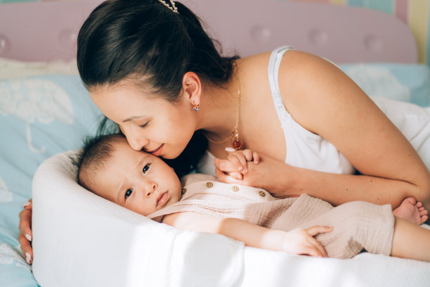 年轻的单身妈妈亲吻她的混血宝宝。儿童领养与体外受精(IVF)。亚洲宝宝和印度妈妈图片下载