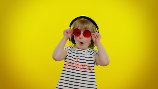 可爱的童女戴着耳机听音乐眨眼，微笑，眨眼，打情骂俏图片下载