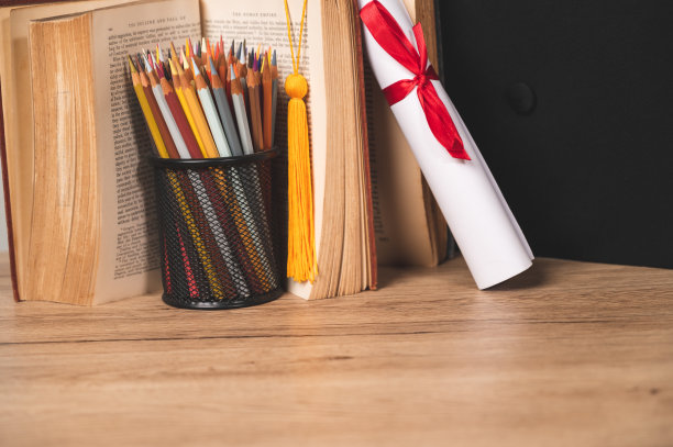 毕业帽，卷好的毕业证书和一个装满彩色铅笔的笔筒图片下载