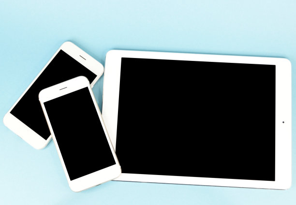 蓝色背景下的平板电脑和两台白色智能手机图片下载