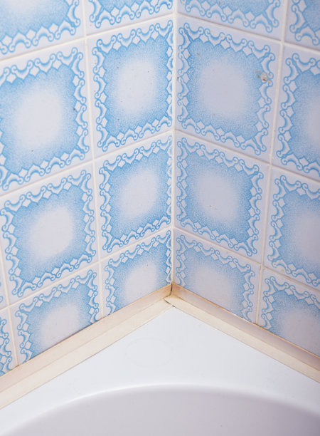 浴室里旧的蓝色瓷砖与一个丙烯酸浴缸相配。图片下载