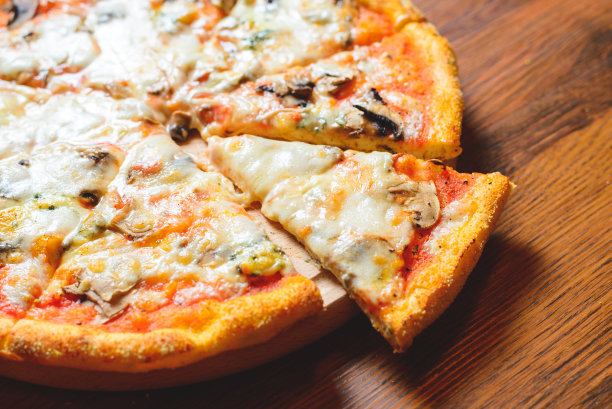 意大利披萨配芝士西红柿，芝麻菜和蘑菇在木砧板库存照片。图片下载