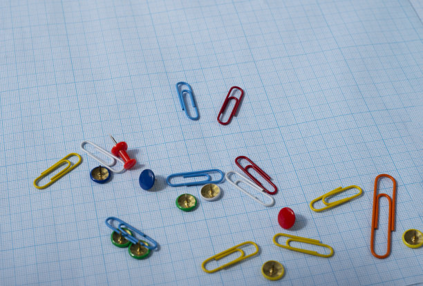 蓝色图纸上的彩色回形针和按钮。为文本复制空间。图片下载