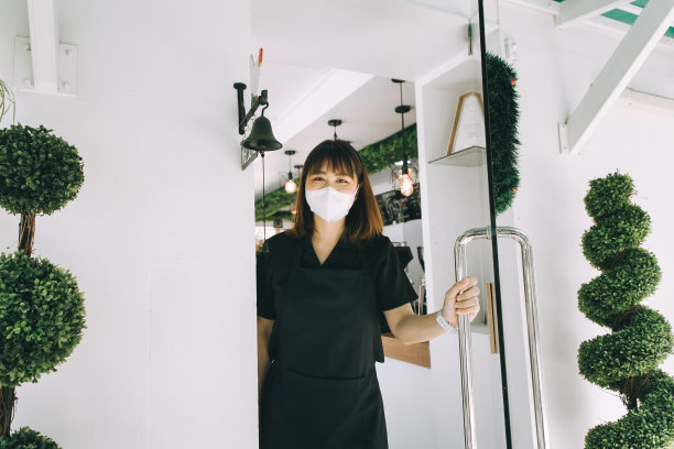 亚洲妇女企业主打开一扇门在一个咖啡馆戴着面具-股票照片图片下载