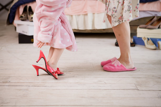 一个小女孩和她的妈妈正在量她们的高跟鞋。在一个房间里开单身派对，穿着睡衣，戴着卷发器图片下载