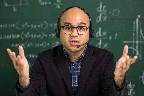 印度年轻教师男子看着摄像机坐在教学在线视频会议直播。亚洲教师戴着耳机课堂授课，为学生在线学习提供在线研讨会。图片下载