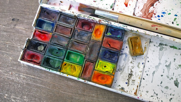 水彩画和画笔放在一个脏盒子里，在一个木制的背景上图片下载