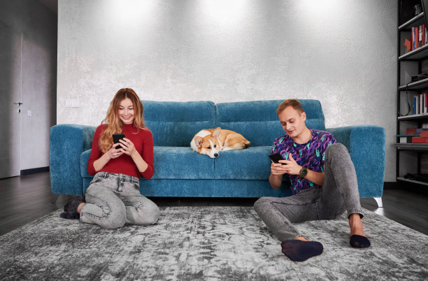 微笑的年轻男子和女子看电话席子。图片下载