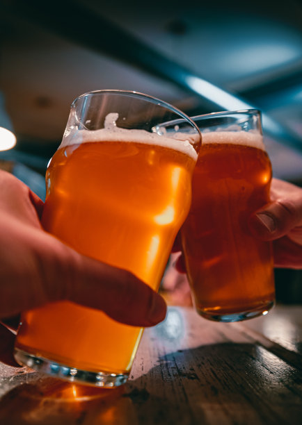 近距离观看两杯啤酒在手。在酒吧里碰杯的啤酒杯图片下载
