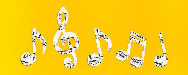 音乐音符和谱号剪自纸上的音乐文本在黄色的背景。网络横幅图片下载