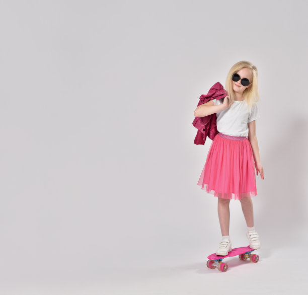 一个穿着粉红色衣服的少女站在滑板上图片下载