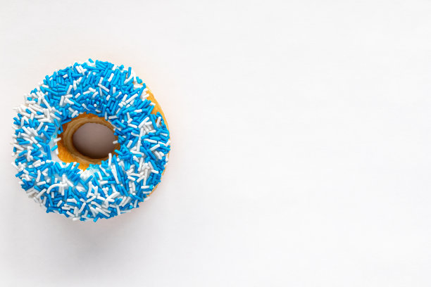 甜甜圈与蓝色和白色点缀在白色背景与复制空间。图片下载