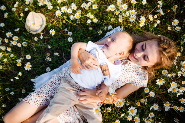妈妈和儿子在绿色的草地上玩耍。图片下载