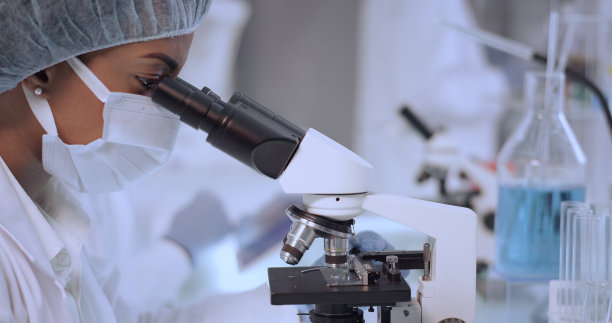 非洲裔，女医生在实验室使用显微镜。在保护面罩中近距离观察脸部。团队背景图片下载