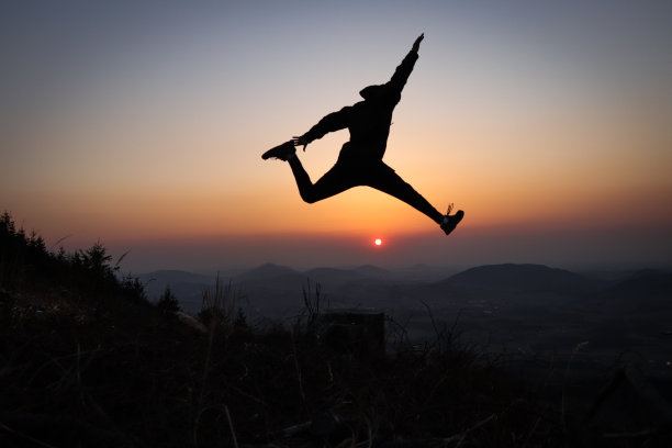 一名少年和一名运动员的剪影在欧洲山区训练爆发力，试图在日落时跳得尽可能高。在自然条件下训练。自我负重训练。图片下载