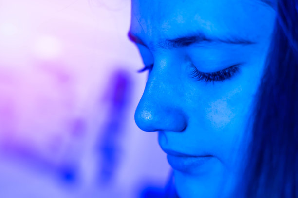 一个十几岁的女孩的肖像思考和观察与蓝色霓虹灯未来迪斯科风格的焦点背景和复制空间选择焦点。图片下载