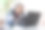 一位老人坐在桌子旁，在电脑上看视频。一个在家里用笔记本电脑工作的老人图片下载