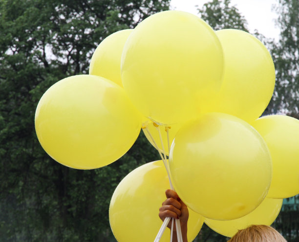 一个女人手里拿着木棍上的黄色气球图片下载