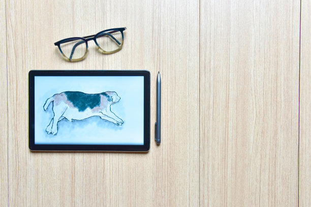 木桌上的比格斯狗的素描图，带数字笔和眼镜的平板，新技术的概念，平板的绘图和渲染图片下载