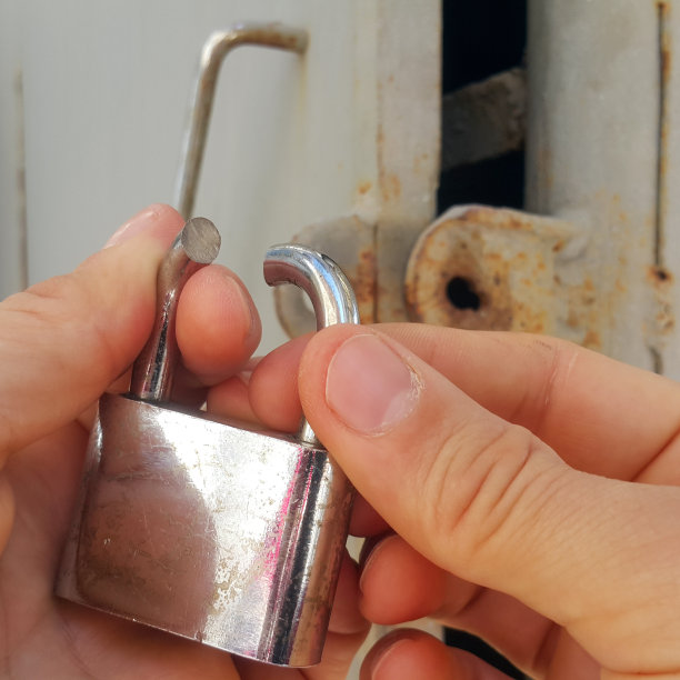 仓库老板手里拿着一把挂锁。锁是用锯子锯掉的。仓库的门开着。发现了一起入室盗窃事件。银行保管箱抢劫。财产损失。图片下载