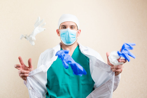 医生边玩边把手套扔了起来。在一个灯光背景上。图片下载