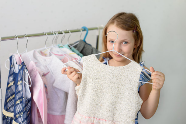 女孩从衣柜的衣架上挑选衣服图片下载