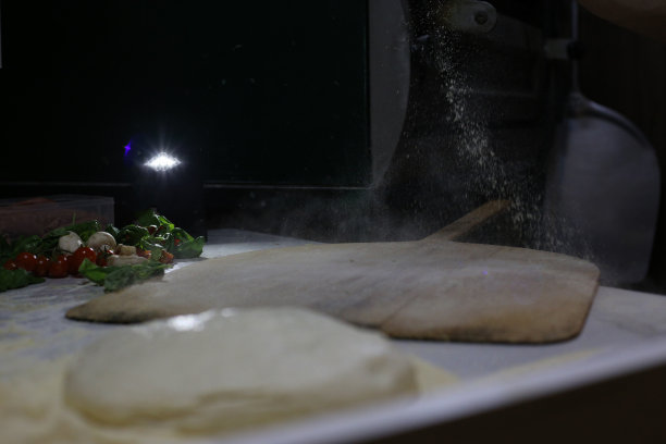 一名厨师在厨房的桌子上撒面粉，并配上了面汤照片图片下载