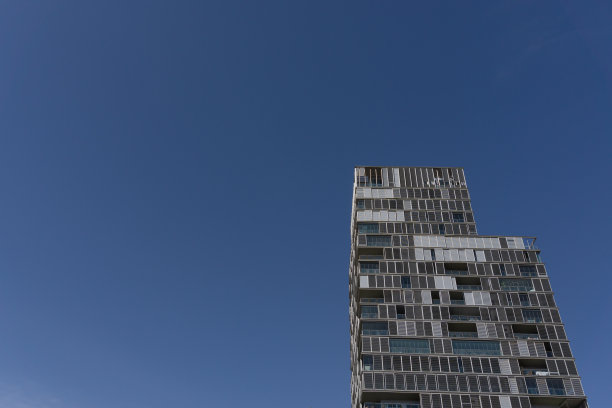 从下面看到一个非常高的建筑，后面是太阳和晴朗的天空图片下载