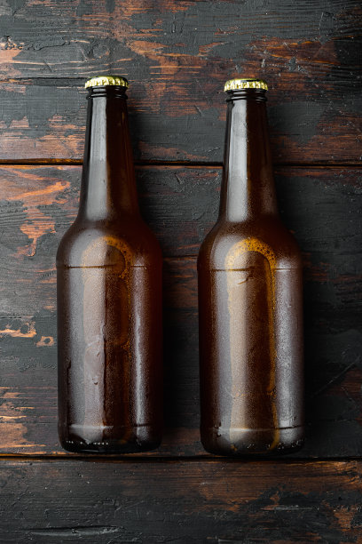 啤酒瓶，放在旧的深色木桌上，俯视图平躺着图片下载