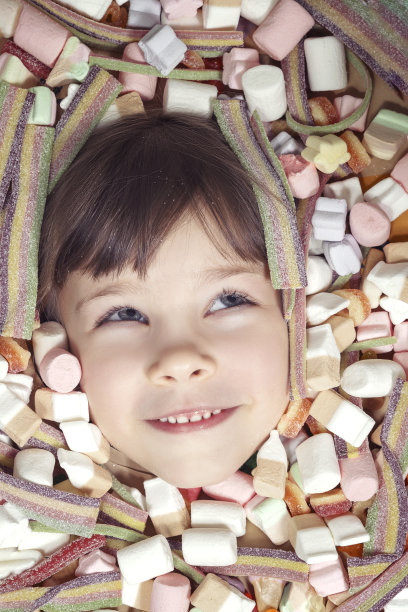 年轻的女孩埋在五颜六色的糖果里图片下载