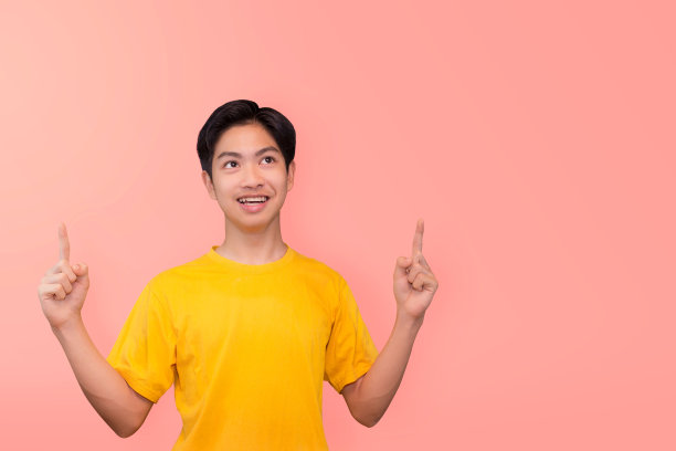 英俊健康的年轻亚洲男子微笑与他的手指孤立在淡粉色横幅背景与拷贝空间图片下载