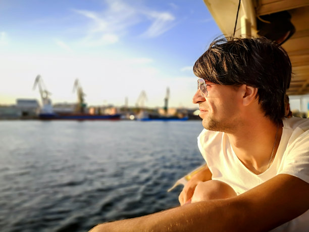 在第聂伯河(乌克兰)上，一个英俊的成年男子在一艘摩托艇的甲板上看着科尔森的全景图。图片下载