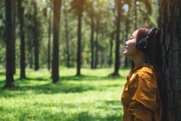 一位年轻漂亮的亚洲女子喜欢在公园里戴着耳机听音乐图片下载
